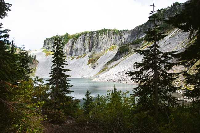 Iceberg Lake, part of the chain lakes, through trees.